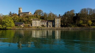An old, well-kept stone castle on the edge of a bay