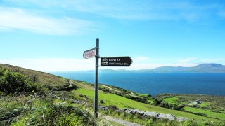 Sheeps head walking trail signpost with the Beara Peninsula across Bantry bay in the distance